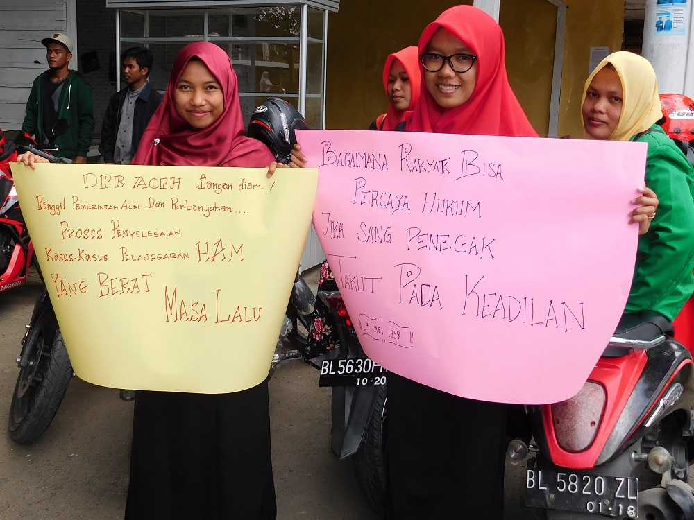 ‘How can the people trust the law when the law enforcers are afraid of justice?’ (Lia Kent) Two Acehnese young women hold up colourful protest signs demanding justice for past human rights violations.